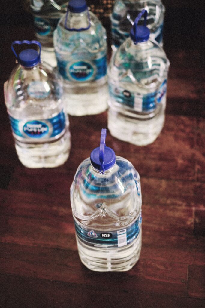 A collection of plastic water bottles with blue caps arranged on a wooden floor, viewed from above.
